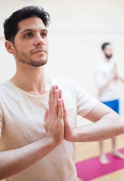 Group of people performing tree-pose yoga exercise in the fitness studio